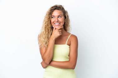 Kıvırcık saçlı kız beyaz arka planda izole edilmiş bir şekilde yukarı bakarken bir fikir düşünüyor.