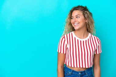 Kıvırcık saçlı kız mavi arka planda izole edilmiş.