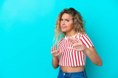 Mavi arka plandaki kıvırcık saçlı kız ellerini öne doğru uzatıyor.