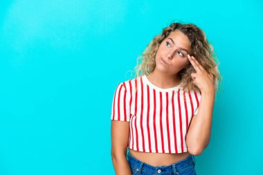 Kıvırcık saçlı kız, mavi arka planda izole edilmiş ve intihar jesti yapmada sorun yaşıyor.