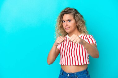 Mavi arka planda kıvırcık saçlı, dövüş jestli bir kız.