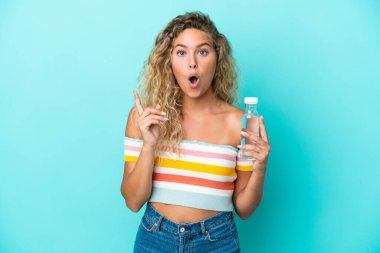 Mavi arka planda izole edilmiş bir şişe suyu olan genç sarışın kadın çözümü bulmak için parmağını kaldırıyor.