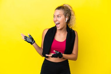 Sarı arka planda havlusu olan sporcu kadın, şaşırmış yüz ifadesi var.