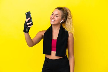 Sarı arka planda izole edilmiş havlusu olan sporcu kadın selfie çekiyor.