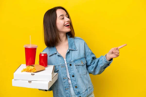 Young Ukrainian Woman Holding Fast Food Isolated Yellow Background Pointing — Stock Photo, Image