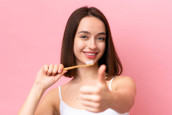 Young Ukrainian woman isolated on pink background with a toothbrush