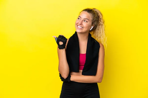 製品を提示するために側面を指す黄色の背景に分離タオルを持つスポーツ女性 — ストック写真