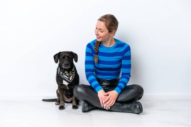 Beyaz arka planda izole edilmiş köpeğiyle yerde oturan beyaz bir kadın mutlu bir ifadeyle.