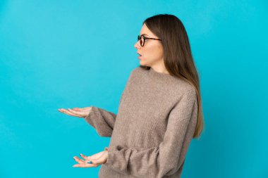 Genç Litvanyalı bir kadın mavi arka planda izole edilmiş.