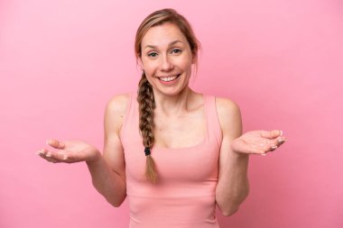 Pembe arka planda izole edilmiş genç beyaz kadın mutlu ve gülümsüyor.