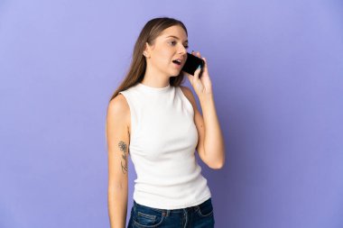 Mor arka planda izole edilmiş genç Litvanyalı kadın cep telefonuyla sohbet ediyor.