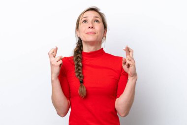 Beyaz arka planda izole edilmiş beyaz tenli genç bir kadın parmaklarını çapraz yapıp en iyisini diliyor.