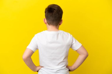 Küçük kızıl saçlı çocuk sarı arka planda izole edilmiş.