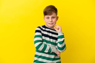 Sarı arka planda izole edilmiş küçük kızıl çocuk gülüyor.