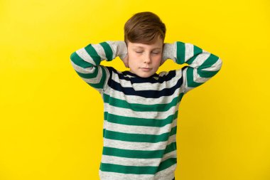 Sarı arka planda izole edilmiş küçük kızıl çocuk hayal kırıklığına uğramış ve kulaklarını kapatmış.