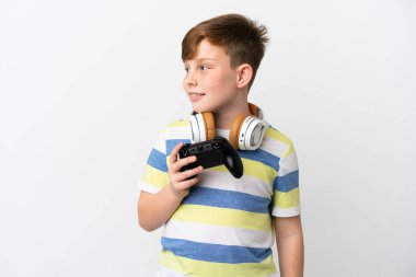 Küçük kızıl saçlı çocuk beyaz arka planda izole edilmiş bir oyun alanı tutuyor.