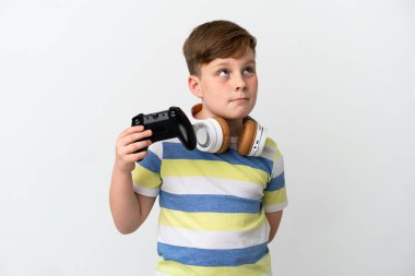 Küçük kızıl saçlı çocuk beyaz arka planda izole edilmiş bir oyun alanı tutuyor ve yukarı bakıyor.