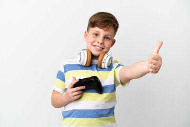 Küçük kızıl saçlı çocuk beyaz arka planda izole edilmiş bir oyun tahtası tutuyor. Başparmakları havada çünkü iyi bir şey oldu.