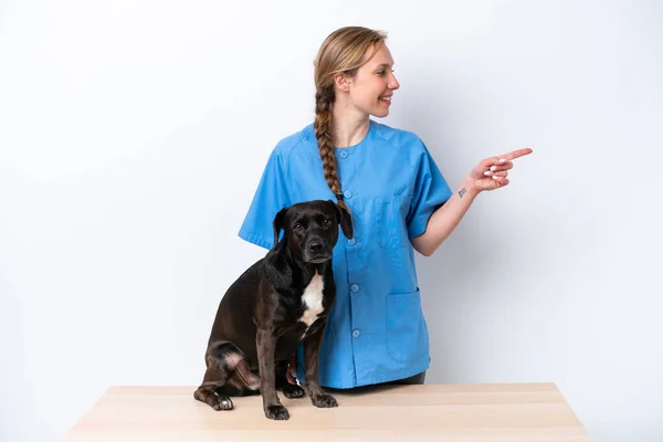 Young veterinarian woman with dog isolated on white background pointing to the side to present a product