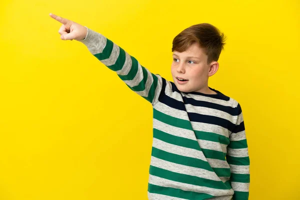 Little Redhead Boy Isolated Yellow Background Pointing Away — 图库照片