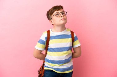 Küçük kızıl saçlı beyaz çocuk pembe arka planda izole edilmiş ve yukarı bakıyor.