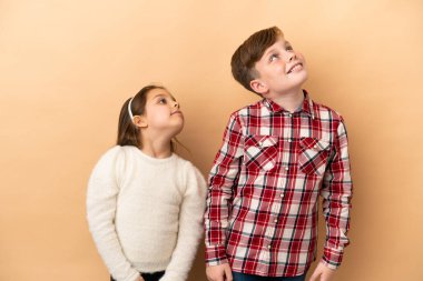 Kafkasyalı küçük kardeşler bej arka planda izole edilmiş.