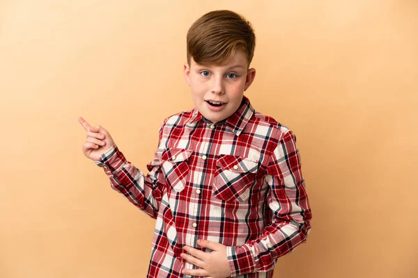 Little Redhead Boy Isolated Beige Background Surprised Pointing Finger Side — Photo