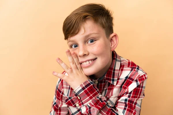 Bej arka planda izole edilmiş küçük kızıl saçlı çocuk.