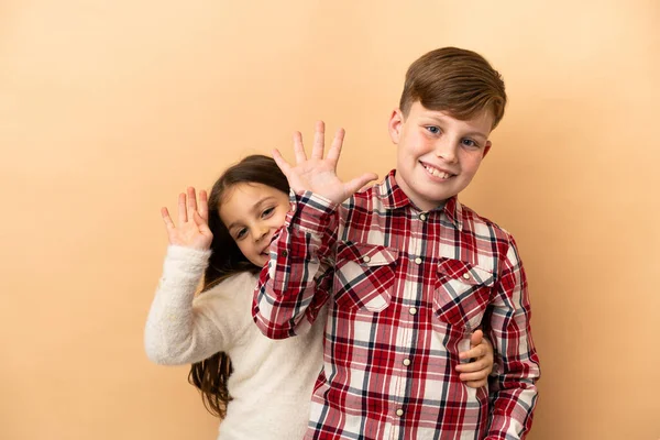 Kafkasyalı küçük kardeşler bej arka planda izole edilmiş.