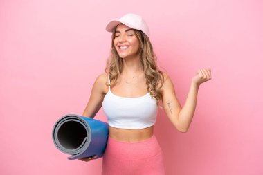 Genç sporcu kadın yoga derslerine giderken elinde bir minder ile zaferi kutluyor.