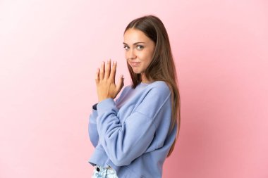 Soyutlanmış pembe arka plan entrikaları kuran genç bir kadın.