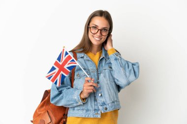 Birleşik Krallık bayrağını izole edilmiş beyaz arka planda tutan genç İspanyol kadın gülüyor.