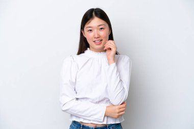 Genç Çinli bir kadın beyaz arka planda yalnız gülüyor.