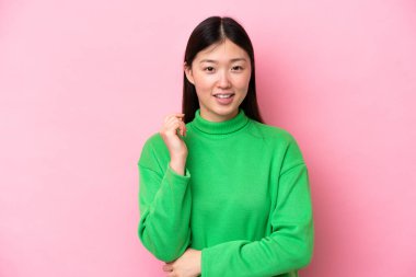 Genç Çinli kadın pembe arka planda yalnız gülüyor.