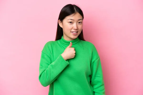 一个年轻的中国女人 被粉色背景隔离 伸出一个大拇指 做一个手势 — 图库照片
