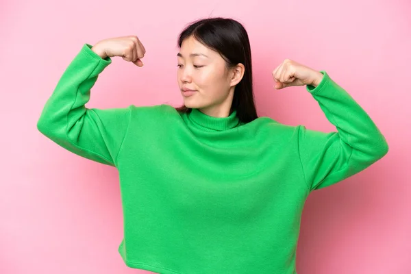 年轻的中国女人有着粉红的背景 做着强有力的手势 — 图库照片