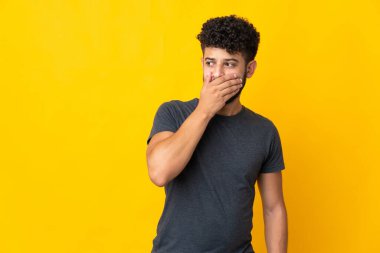 Sarı arka planda izole edilmiş genç Faslı bir adam yan tarafa bakarken sürpriz jest yapıyor.