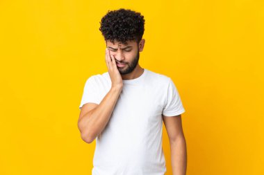 Sarı arka planda diş ağrısı olan genç Faslı bir adam izole edilmiş.