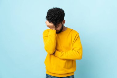 Faslı genç bir adam mavi arka planda başağrısı ile izole edilmiş.