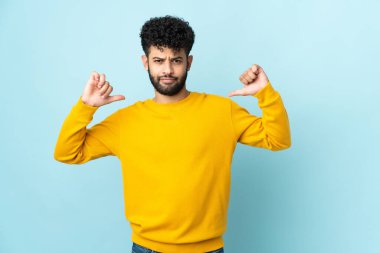 Genç Faslı adam mavi arka planda soyutlanmış gururlu ve kendini beğenmiş.