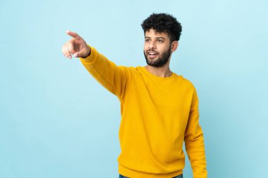 Faslı genç bir adam mavi arka planda izole edilmiş.