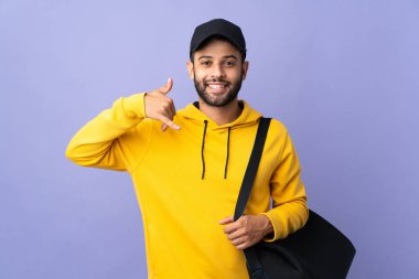 Morarmış arka planda izole edilmiş spor çantalı Faslı genç bir adam telefon jesti yapıyor. Bana geri dönüş işareti ver.