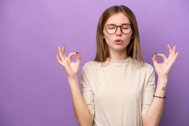 Mor arka planda izole edilmiş genç İngiliz kadın zen pozu