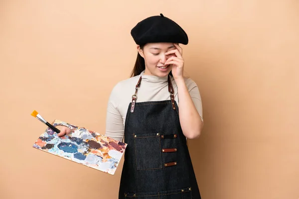 Joven Pintora China Aislada Sobre Fondo Beige Riendo —  Fotos de Stock