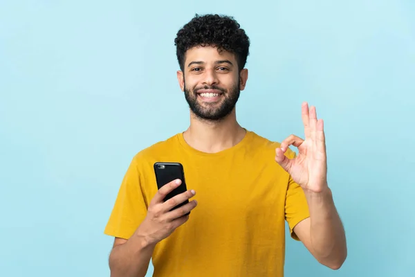 Jonge Marokkaanse Man Geïsoleerd Blauwe Achtergrond Met Behulp Van Mobiele — Stockfoto