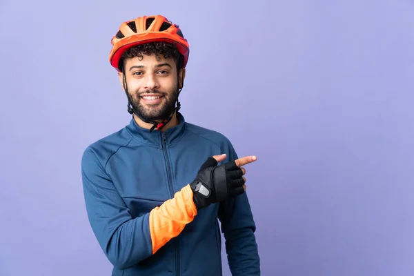 Joven Ciclista Marroquí Aislado Sobre Fondo Púrpura Apuntando Con Dedo — Foto de Stock