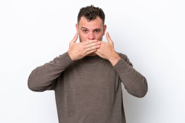 Genç Brezilyalı bir adam beyaz arka planda izole edilmiş. Ağzı elleri ile kapatıyor.