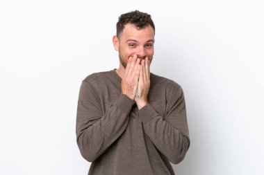 Genç Brezilyalı bir adam beyaz arka planda izole edilmiş mutlu ve gülümseyen elleriyle ağzını kapatıyor.