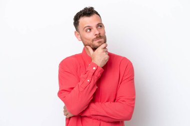 Genç Brezilyalı bir adam beyaz arka planda izole edilmiş bir şekilde bakarken bir fikir düşünüyor.