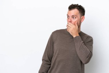 Beyaz arka planda izole edilmiş genç Brezilyalı adam yan tarafa bakarken sürpriz jest yapıyor.